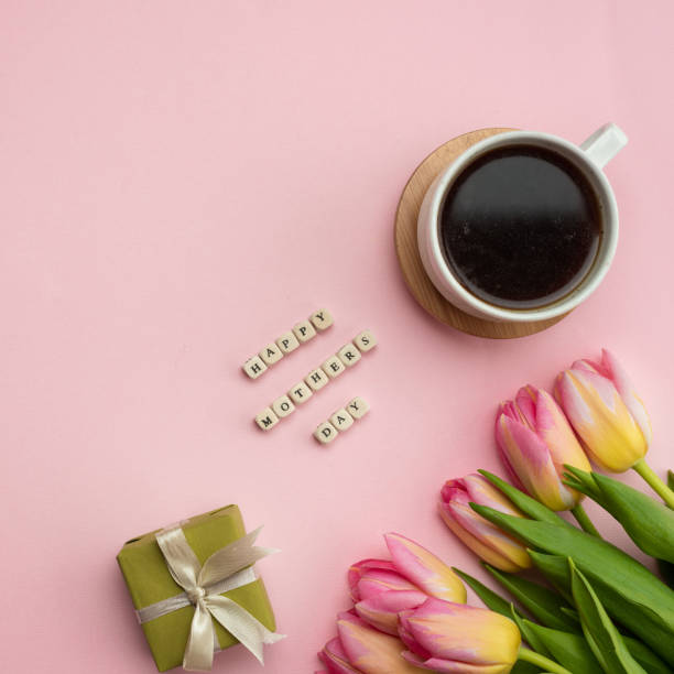 Mother's Day greeting message with tulips, gift and coffee on pink background. Background for International Mother Day. stock photo