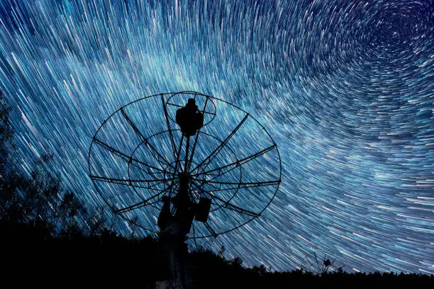 radiotelescopes silhouettes under short star trails background