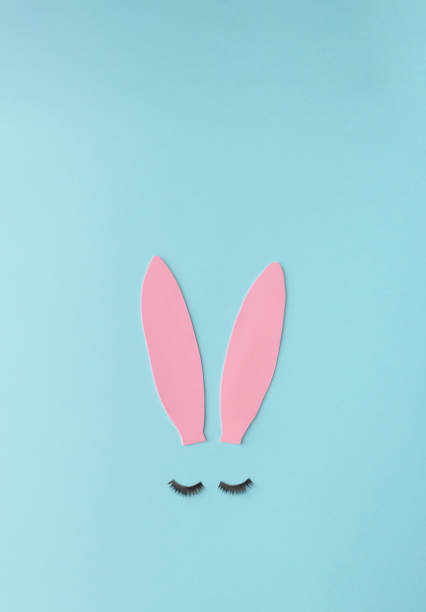 Bunny ears made of pink foam on a blue background. Easter concept. Flat lay. Minimal style.
