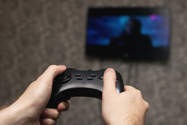 istock Game joystick in hands on background of TV 1306965136