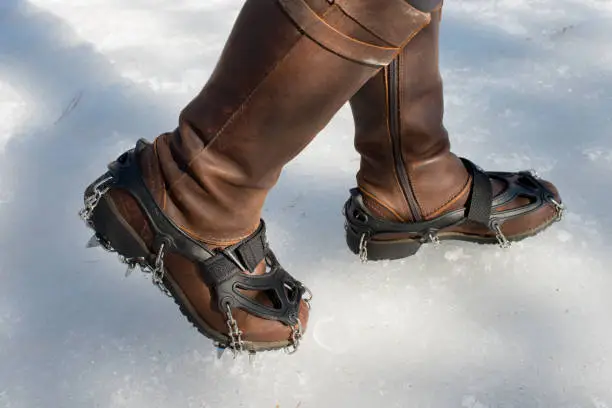 Photo of Steel traction cleats for ice on female leather booths on icy hiking trail in Canada