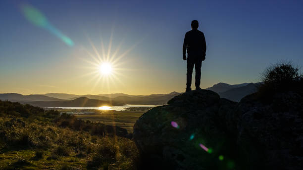 istock Man standing on a rock with his back facing the sunset over the mountains. Navacerrada Madrid. 1306970435