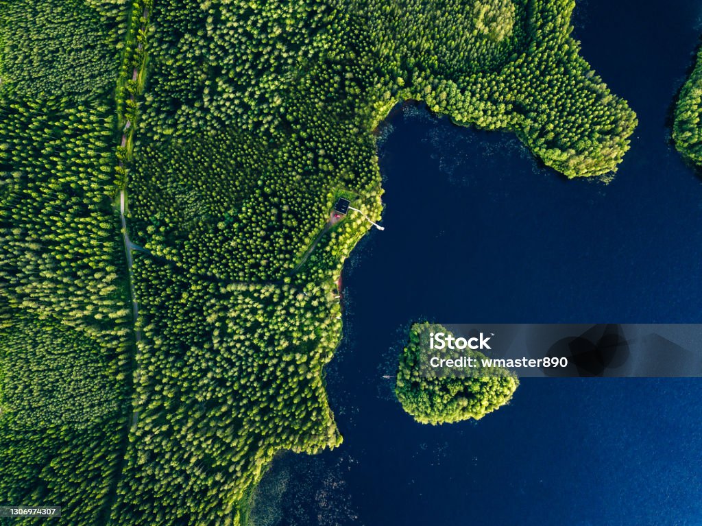 Aerial view of green forests with blue lake and summer cottage with wooden pier Aerial view of green forests with blue lake and summer cottage with wooden pier in Finland Aerial View Stock Photo