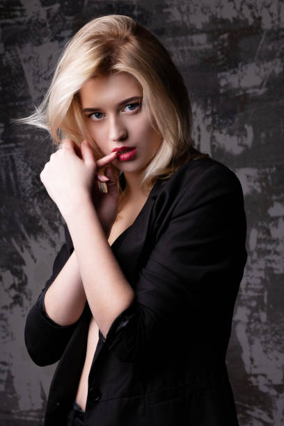 istock Beautiful blonde model wearing black jacket posing at studio with shadows 1306974769