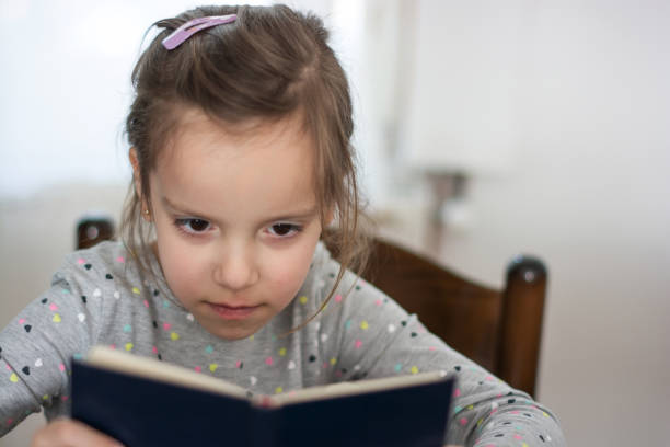 istock Little girl reading a book at home 1306975397