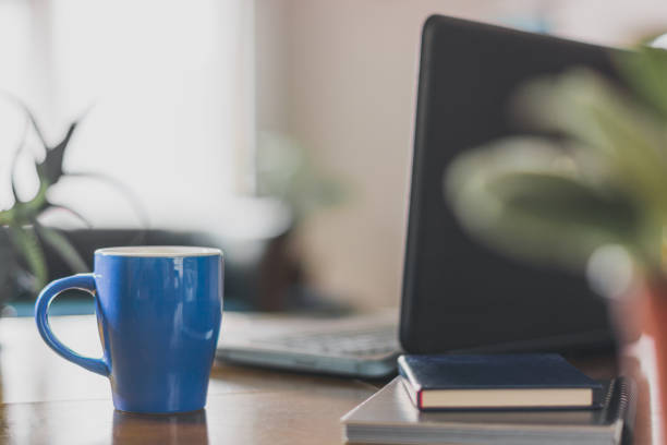 Desk with blue coffee cup and laptop