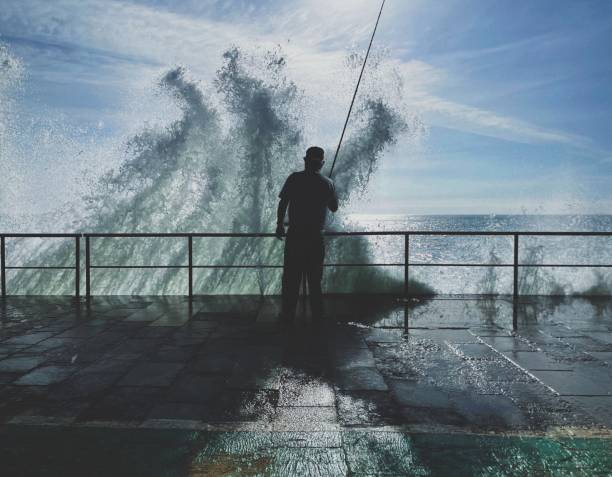 istock Man fishing hit by a wave 1306976760