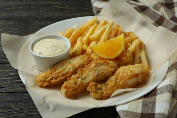 istock Plate with fried fish and chips on wooden background with kitchen towel 1306978885