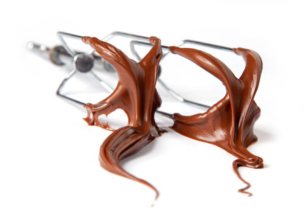 istock whisk whit melted chocolate cream isolated on white background, selective focus 1306985261