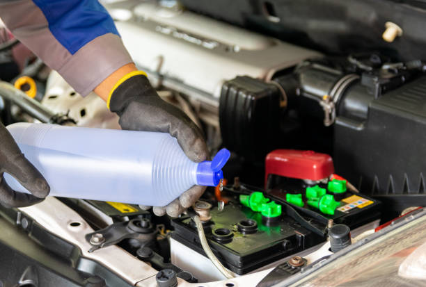 el mecánico añade agua destilada y revisa la batería del coche - distilled water fotografías e imágenes de stock