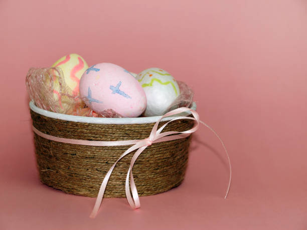 istock painted easter eggs in a decorative bowl with a bow on a pink background copy space 1306996385