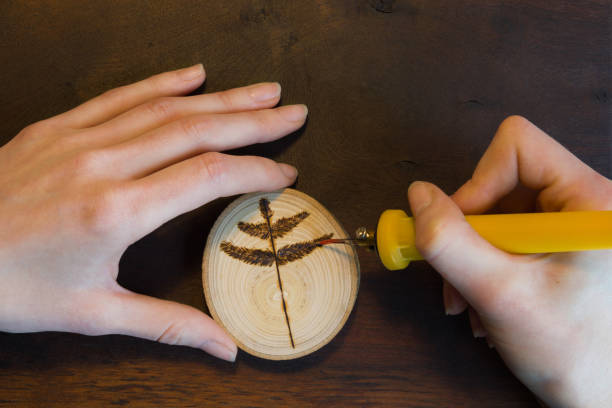 Photo of Close-up of female hands making a tree twig sign on wooden disc.