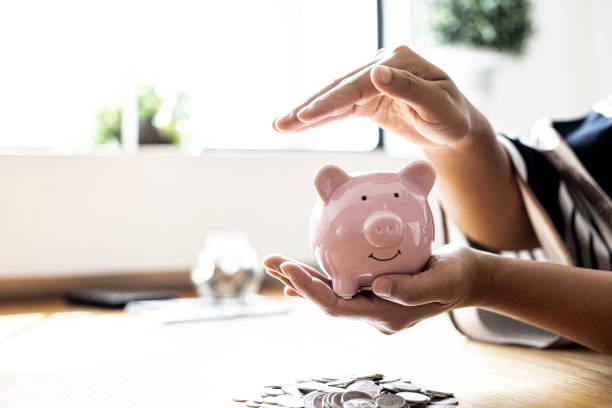 une femme tenant une tirelire en forme de cochon rose, elle organise de l’argent pour le diviser en épargne et acheter des fonds pour le faire pousser. concept de finances personnelles. - gold paying internet credit card photos et images de collection