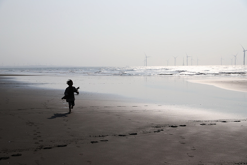 silhouette of a asian girl playing and running on beach