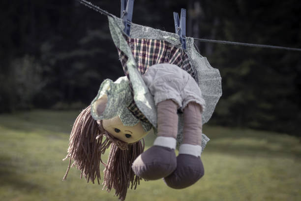 violence against children concept, abandoned red haired doll in dress hang on a rope - paedophilia imagens e fotografias de stock