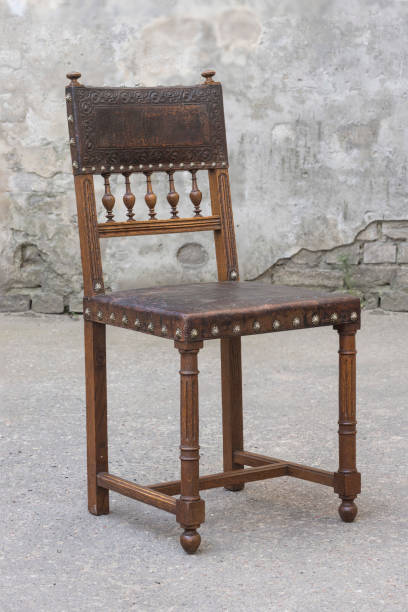 istock Vintage Oak Chair with leather and decorative nails on gray wall background 1307006024