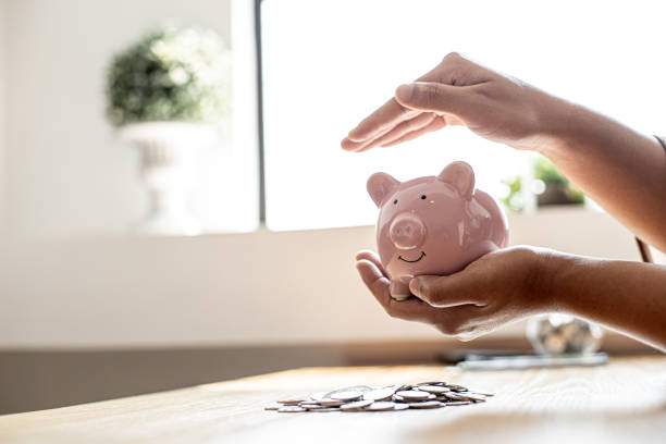 une femme tenant une tirelire en forme de cochon rose, elle organise de l’argent pour le diviser en épargne et acheter des fonds pour le faire pousser. concept de finances personnelles. - gold paying internet credit card photos et images de collection