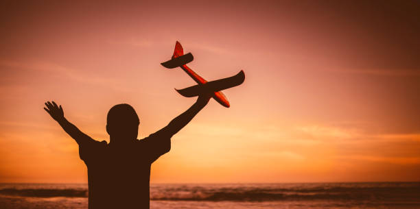 istock Silhouette boy playing aeroplane toy on beach in evening 1307007199