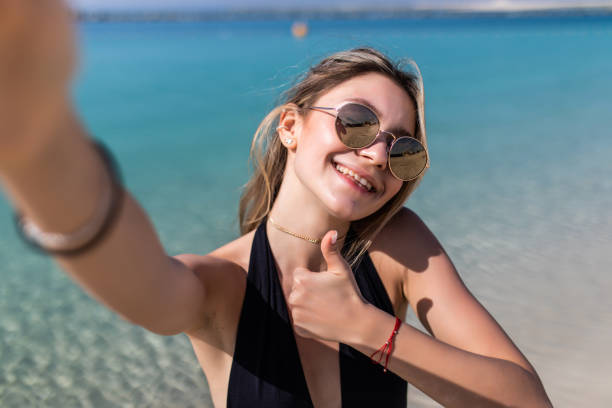 istock Beautiful young woman doing selfie on the beach 1307007246