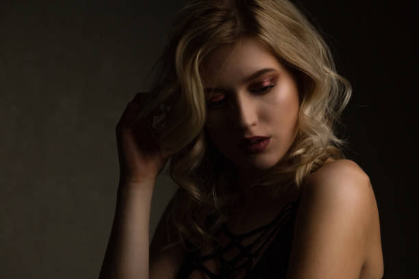 istock Sensual blonde model with perfect makeup and naked shoulders posing with contrast light. Empty space 1307007309