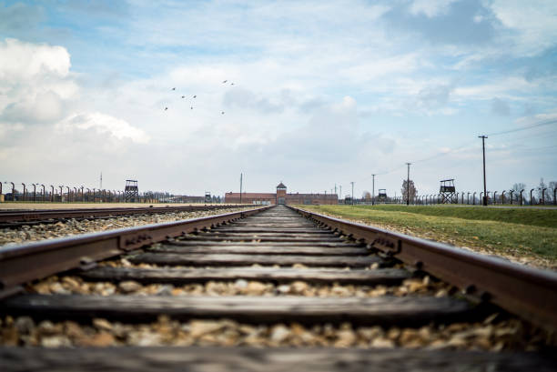 Auschwitz Birkenau II Concentration and Extermination Camp Oswiecim Poland - Oct 17 2019 Low angle train tracks sorting ramp through holocaust lookout guard tower gatehouse train entrance no people.