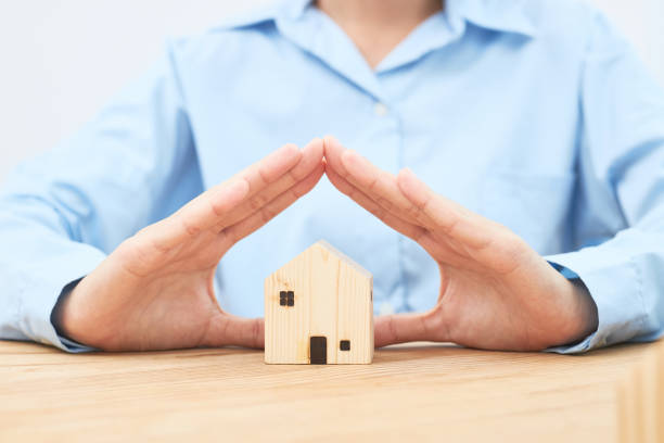 istock Female hands showing protect a wooden house. 1307008980