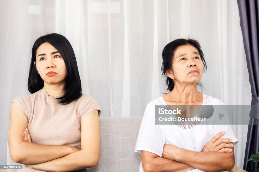 depressed Asian mother and daughter sitting at sofa angry, quarrel, ignoring each other , serious relationship in family depressed Asian mother and daughter sitting at sofa angry, quarrel, ignoring each other , serious relationship in family concept Asian and Indian Ethnicities Stock Photo