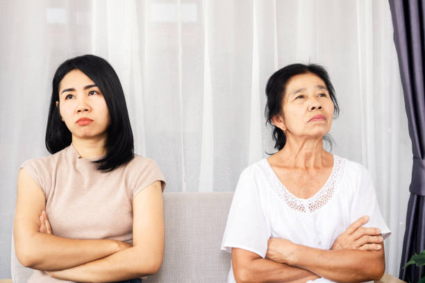 депрессии азиатских мать и дочь, сидя на диване сердиться, ссоры, игнорируя друг друга, серьезные отношения в семье - distraught 70s asian ethnicity women стоковые фото и изображения