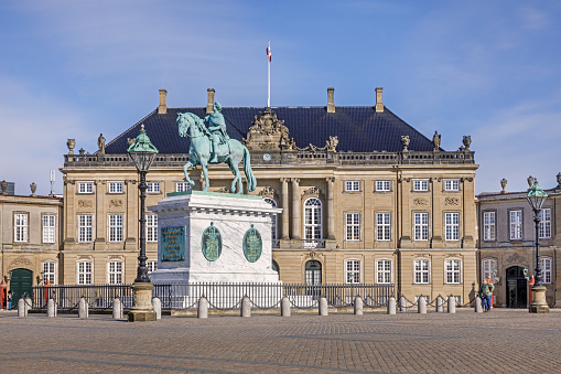 The King is in, the Royal's flag is flying over their mansion. Two Guards are visible in their guard kiosks, there are many more around the building, the grounds of which are open to the general public.