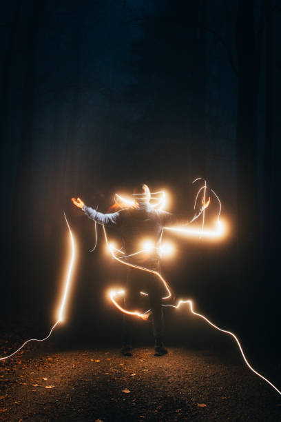 istock boy in the blue jacket is surrounded by yellow light in the dark. Visual effects at night. Long exposure and playing with light. The mystical environment brings us into the fantasy world 1307012296