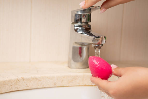 Beautician cleansing cosmetic sponge over sink