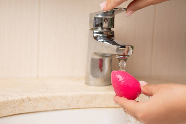 Beautician cleansing cosmetic sponge over sink Beautician cleansing beauty blender after applying makeup. Space for text make up brush stock pictures, royalty-free photos & images