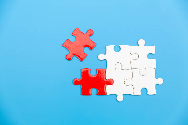 istock White and red jigsaw puzzle on a blue background. Copy space for text, top view, close up. 1307016133