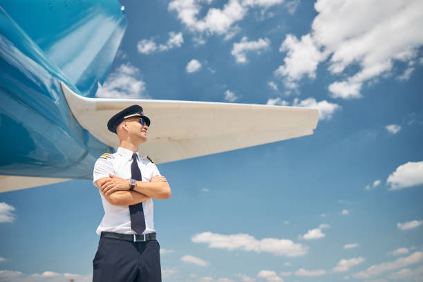 istock Handsome pilot standing by airplane under blue sky 1307016296