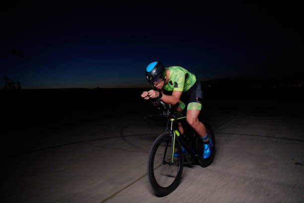 istock triathlon athlete riding bike fast at night 1307019505