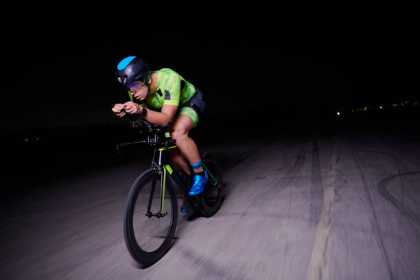 istock triathlon athlete riding bike fast at night 1307019743