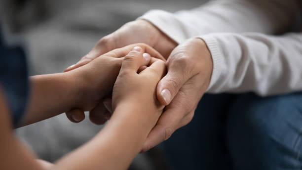 fermez-vous vers le haut de la mère bienveillante touchant les mains adorables de petite fille - multi generation family adoption family human hand photos et images de collection