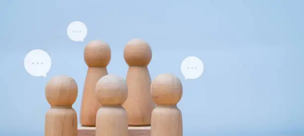 Group of wooden toy people standing together with speech bubble. corporate teamwork concept with copy space