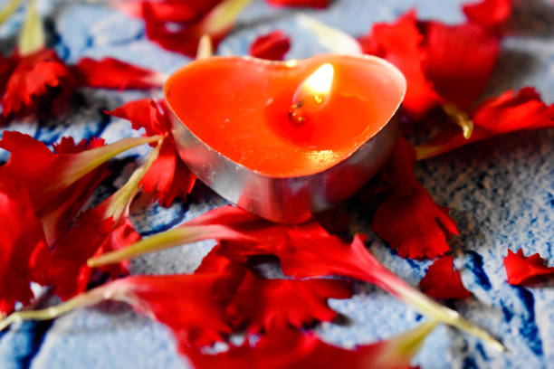 istock Heart shaped red candle and red flower petals on a blue background 1307023738