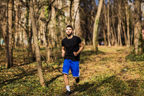 istock Running man in forest woods training and exercising for trail run marathon endurance race. Fitness healthy lifestyle concept with male athlete trail runner. 1307023828