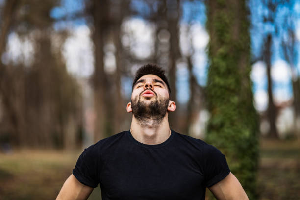 l’homme détendu respire l’air frais dans une belle forêt colorée - exercice de respiration photos et images de collection