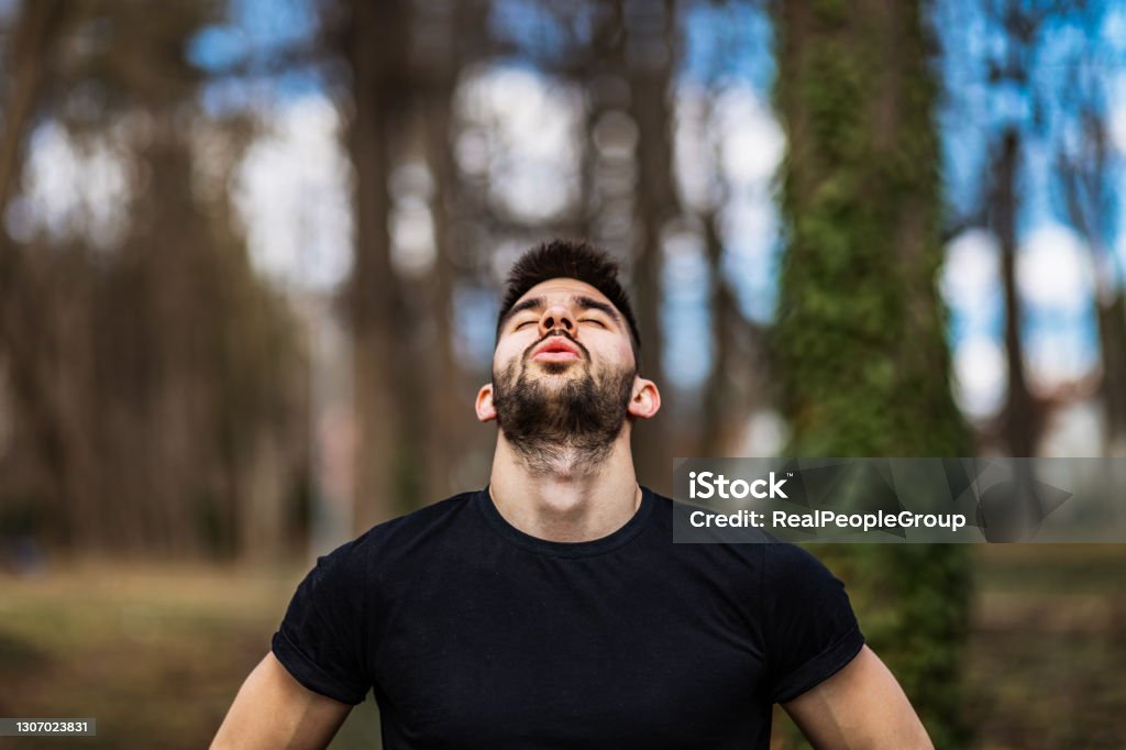 Relaxed man  breaths fresh air in a beautiful colorful forest Happy casual man breathing fresh air in a park with trees in the background Breathing Exercise Stock Photo
