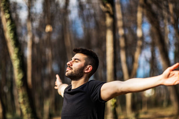istock Young man breathing fresh air stretching arms in a park 1307023851