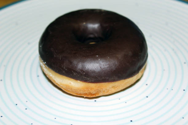 istock One brown chocolate glazed doughnut isolated on blue circles plate 1307023929