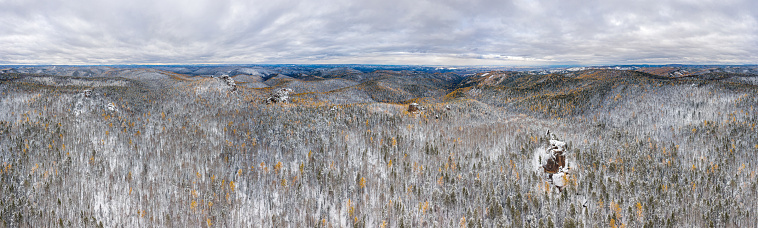 Eastern Sayans. Panorama of the Krasnoyarsk Pillars National Park. Siberian taiga in winter. Aerial view. Original dimensions: 28977px х 8722px.