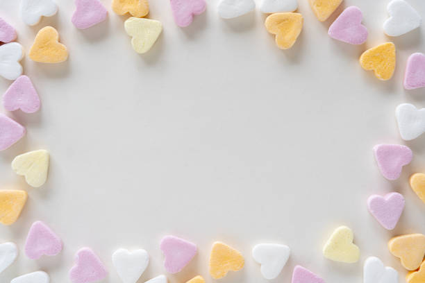 istock Heart shaped colorful candy on white background with copy space, sweets in pink, white, yellow, orange, pink pastels 1307027563