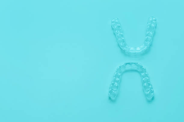 istock Invisible dental teeth brackets tooth aligners on turquoise background. Plastic braces dentistry retainers to straighten teeth. 1307027620