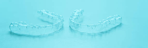 istock Invisible dental teeth brackets tooth aligners on turquoise background. Plastic braces dentistry retainers to straighten teeth. 1307029322