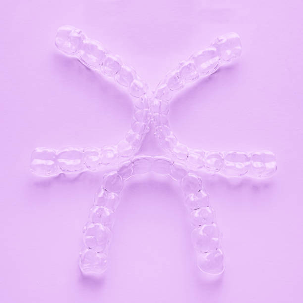 istock Invisible dental teeth brackets tooth aligners on pink background. Plastic braces dentistry retainers to straighten teeth. 1307029480