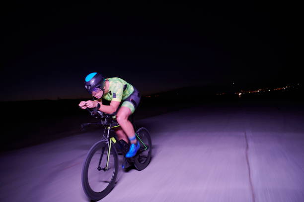 istock triathlon athlete riding bike fast at night 1307030044
